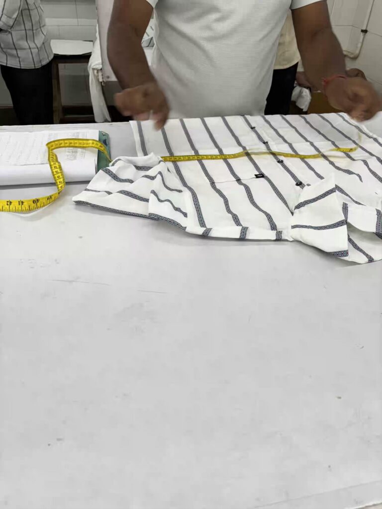 Quality controller measuring a garment against the approved specification, Myra Enterprises Noida India