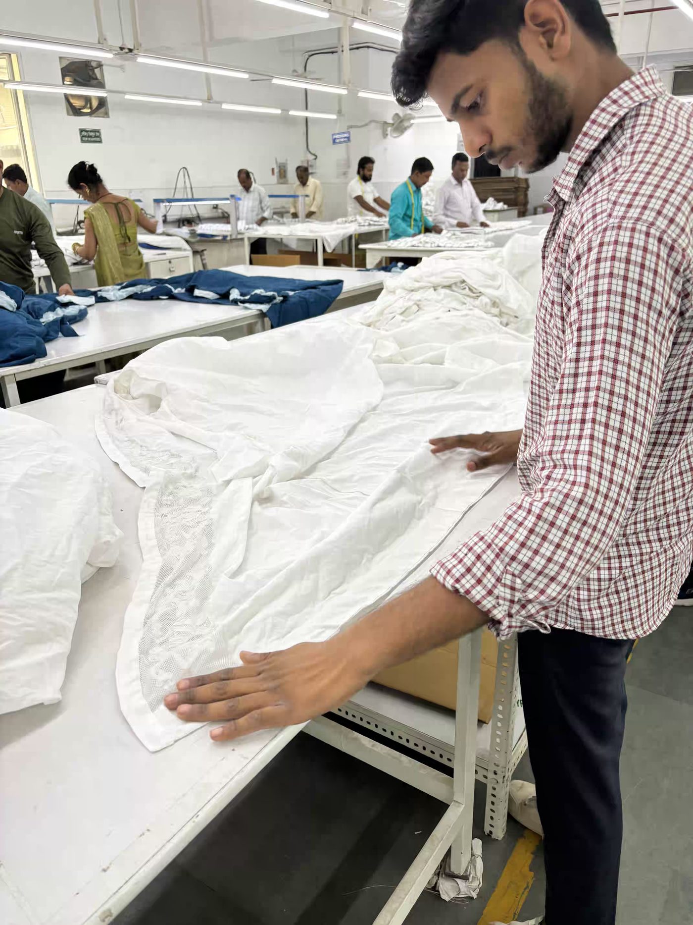 Inspecting a finished garment during quality control at Myra Enterprises, Noida
